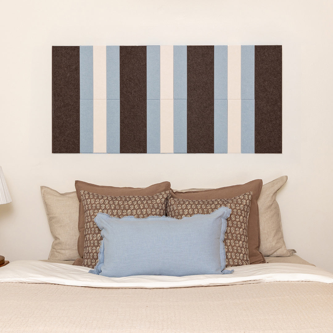 Striped wall art above a bed with decorative pillows