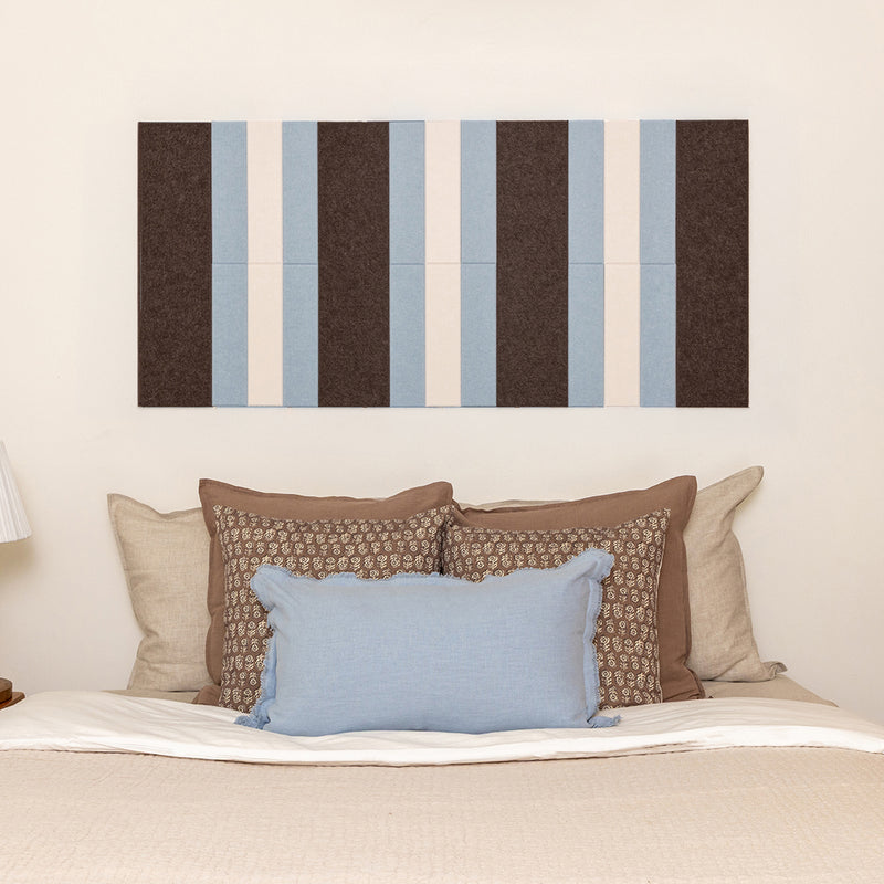 Striped wall art above a bed with decorative pillows