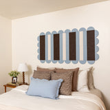 Decorative wall art above a bed with pillows and a lamp.