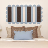 Bed with decorative pillows and a wall art piece with horizontal stripes.