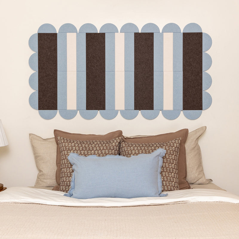 Bed with decorative pillows and a wall art piece with horizontal stripes.