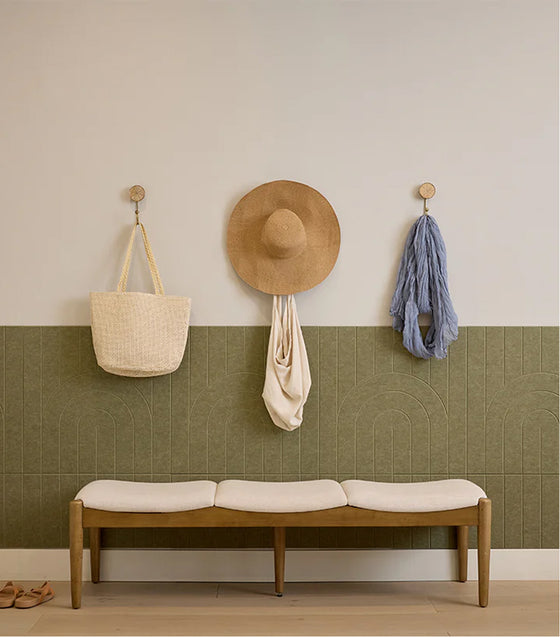 Wall with hooks holding bags and a hat, featuring a wooden bench with a cushion.