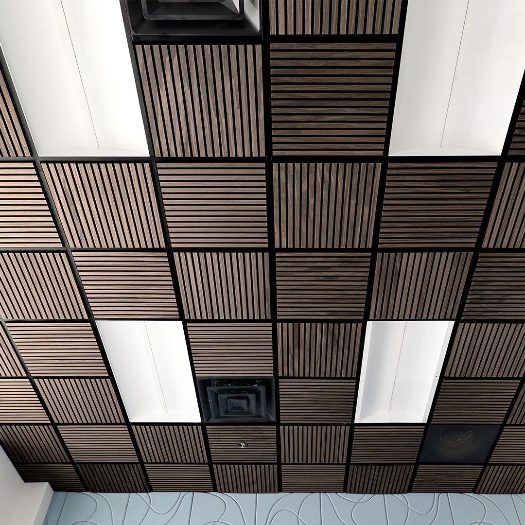 A ceiling grid of square acoustic tiles, featuring alternating dark brown wood-grain slatted panels and white rectangular panels, with black metal grout lines.