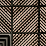 Close-up of a geometric patterned surface with alternating rectangular panels featuring diagonal black stripes on a warm beige background, separated by black grout or trim lines.