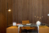 Modern office desk with chair against a wooden paneled wall.