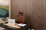 Modern office desk with laptop, chair, and decor against a slatted wood wall.