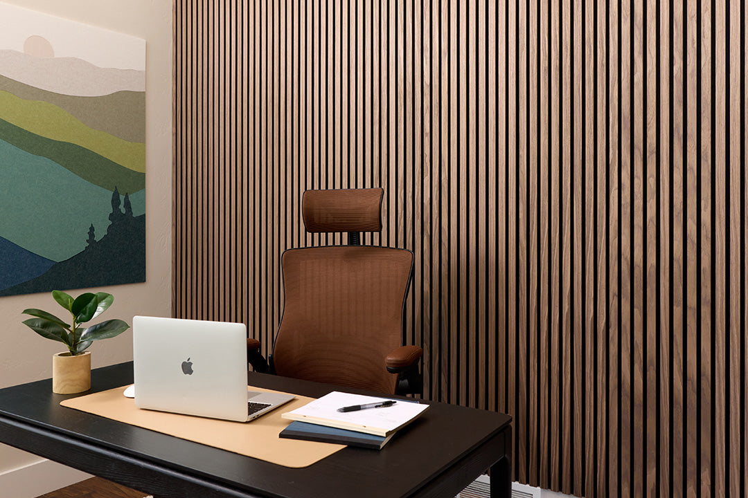 Modern office desk with laptop, chair, and decor against a slatted wood wall.