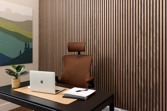 Modern office desk with laptop, chair, and decor against a slatted wood wall.