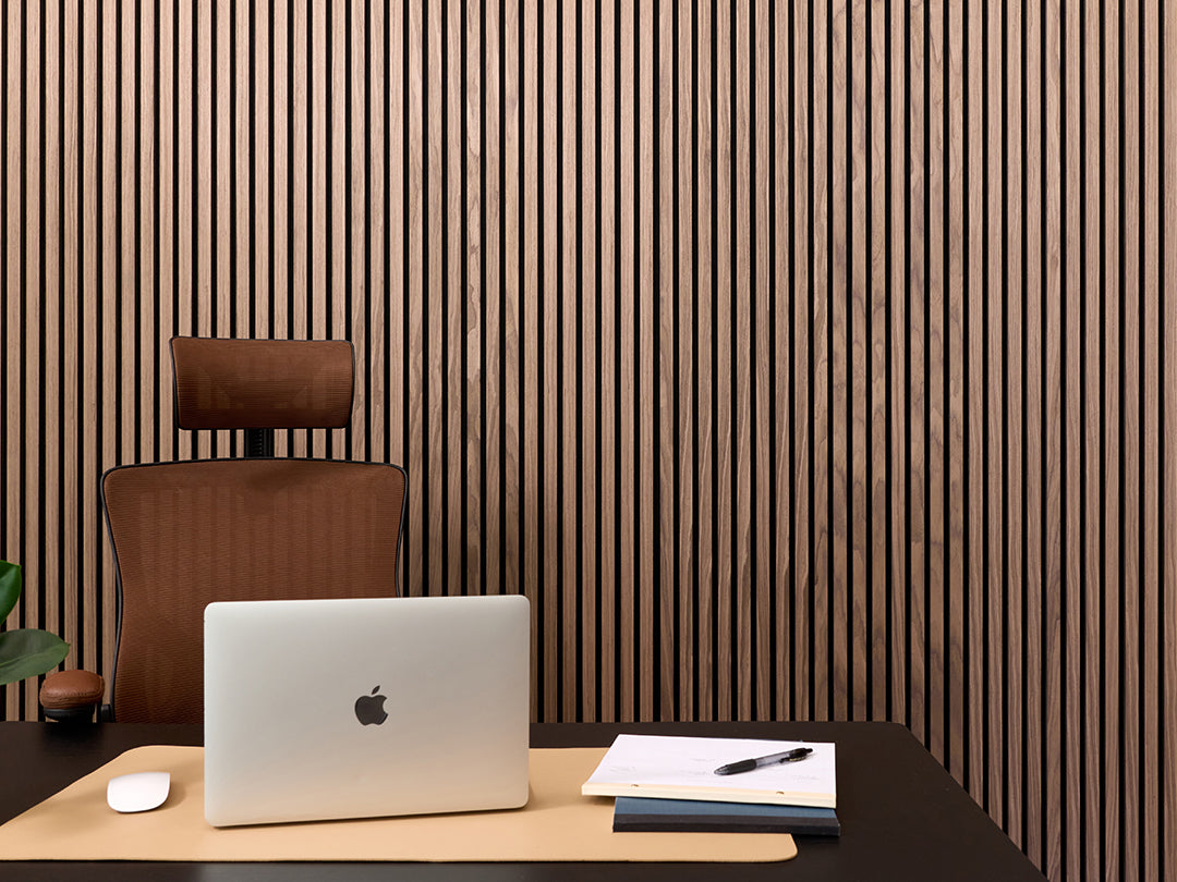 Modern office setup with a laptop, chair, and desk against a slatted wooden wall.
