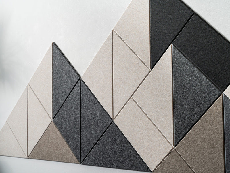 A Felt Right modern wall-mounted art piece resembling a mountain range, composed of triangular panels in shades of beige, gray, and black, on a white wall