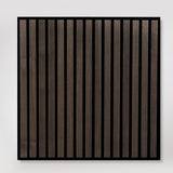 A square wall-mounted decorative panel featuring vertical dark brown wood slats with a thin black frame, shown against a light gray wall.