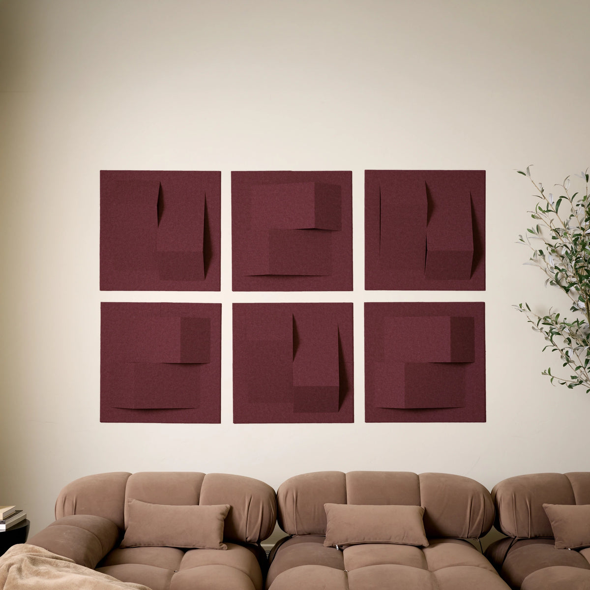 Red-purple acoustic felt wall tiles arranged in a a modern geometric design above a couch