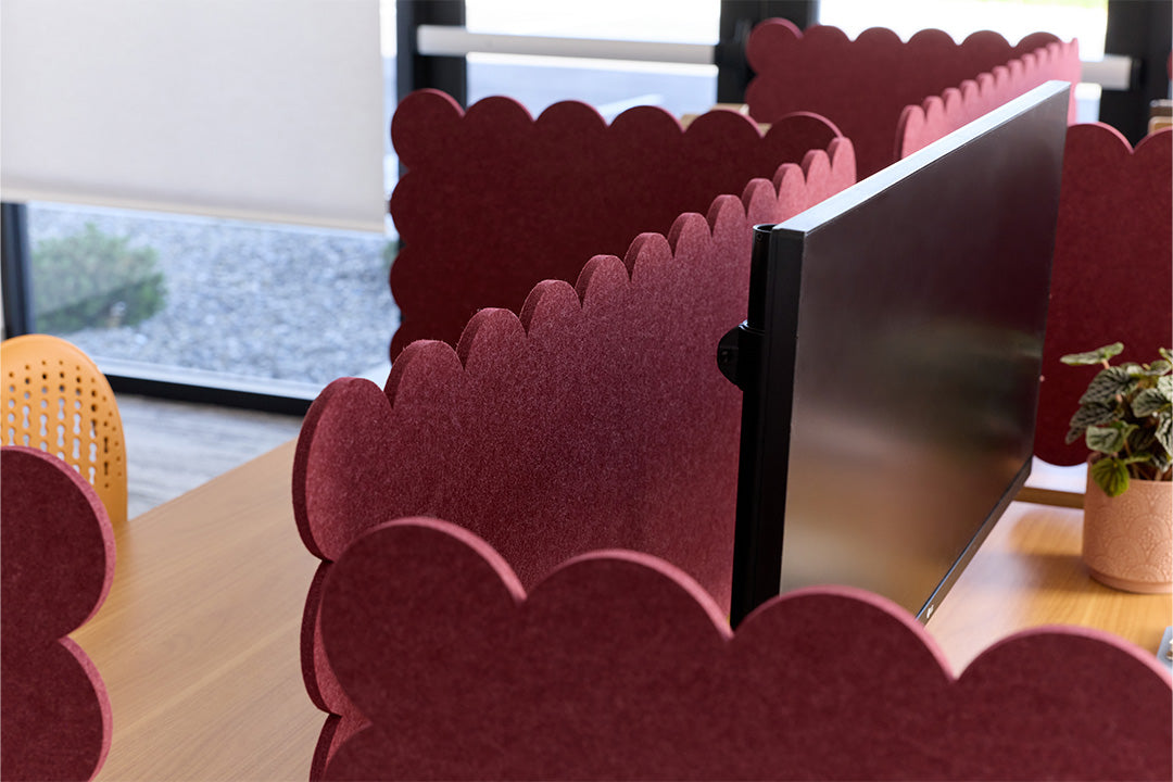 Red scalloped office partitions with computer monitors in a modern office setting.
