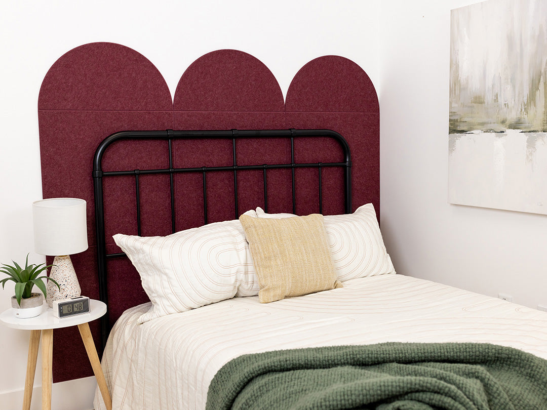 A Felt Right wall design as a head board for a bed in a bedroom in shade of dark red in a scallop pattern.