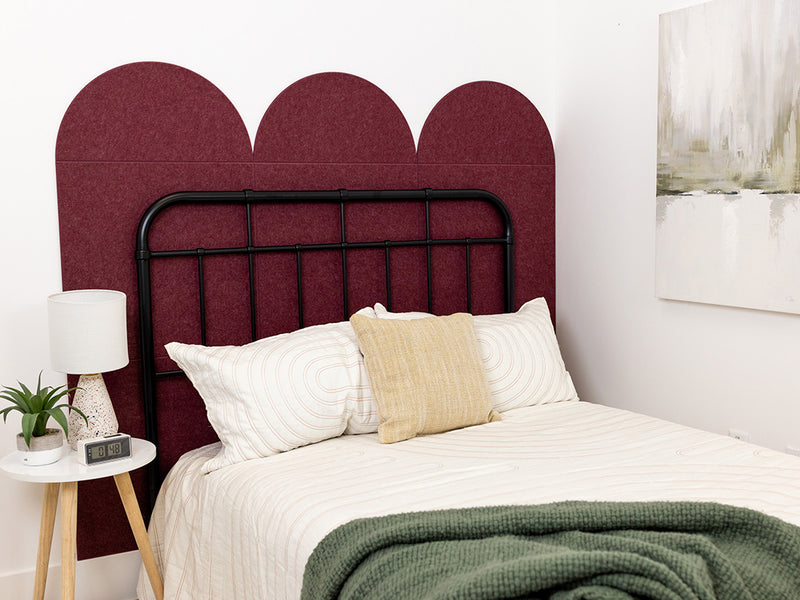 A Felt Right wall design as a head board for a bed in a bedroom in shade of dark red in a scallop pattern.