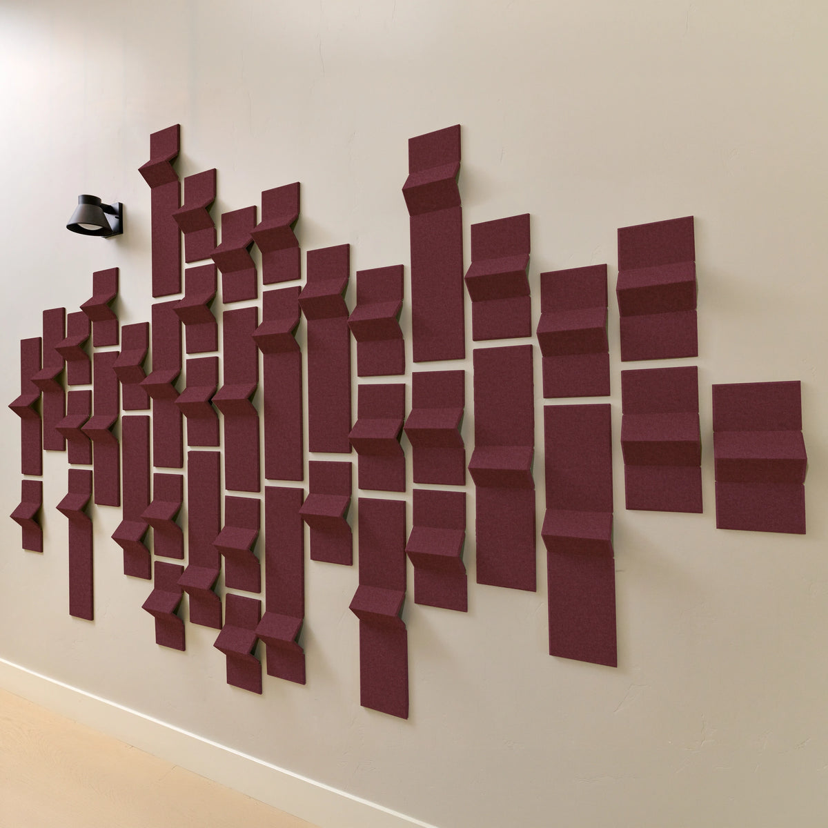 Dark red acoustic felt tiles with points that resemble peaks along a wall