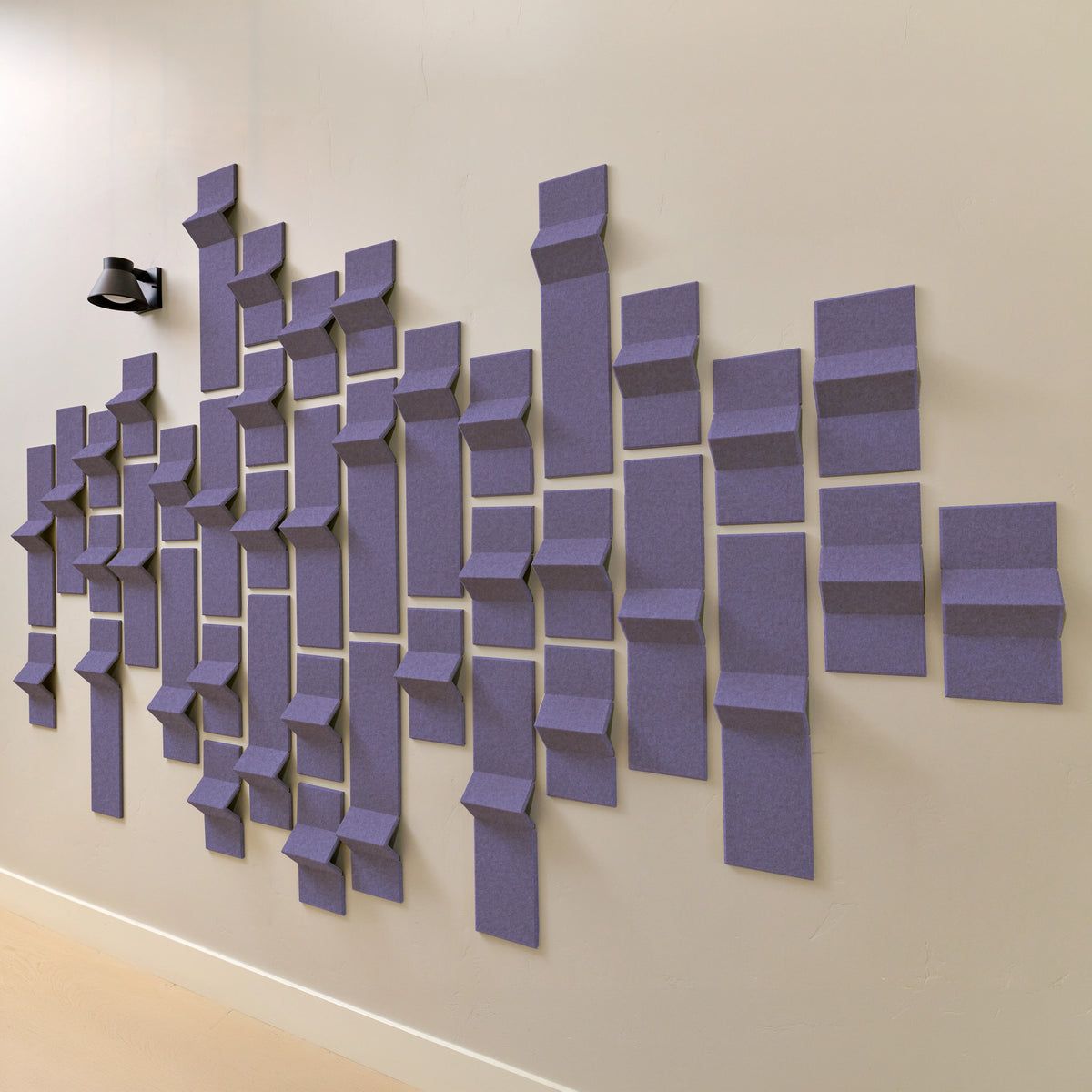 Soft purple felt acoustic tiles along a wall with a hallway light