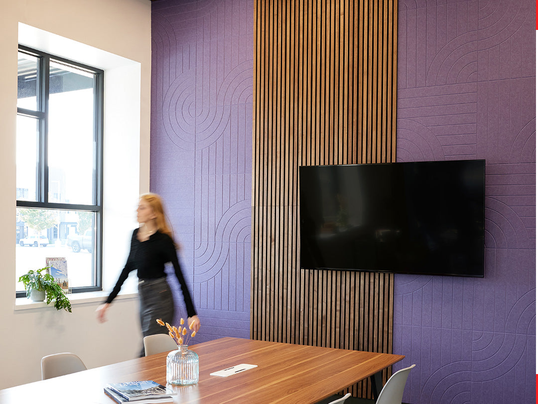 A Felt Right wall art design in shade of purple with wood panelling in a conference room with a tv on the wall and a big conference table.