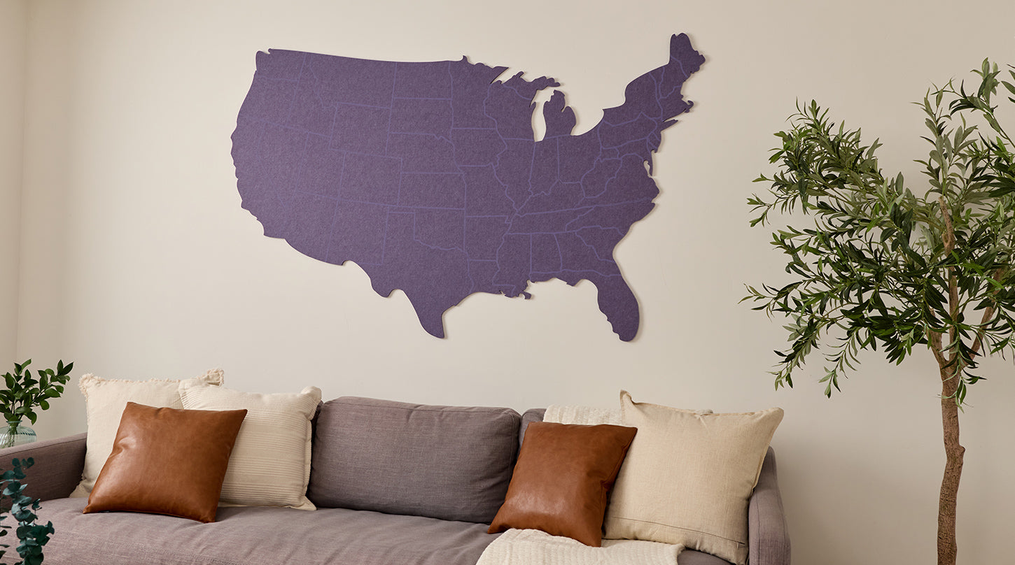 Purple map of the United States on a wall above a sofa with decorative pillows.