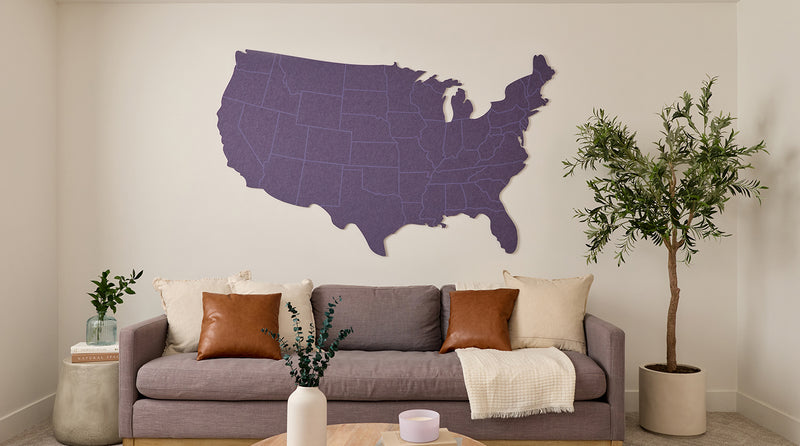 Living room with a gray sofa, decorative pillows, and a large map of the United States on the wall.