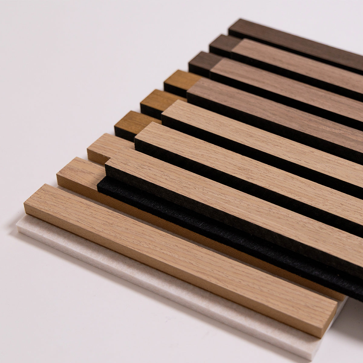 A stack of rectangular wood slats samples in multiple natural wood tones, including light tan, medium brown, and dark brown, arranged on a plain light background.
