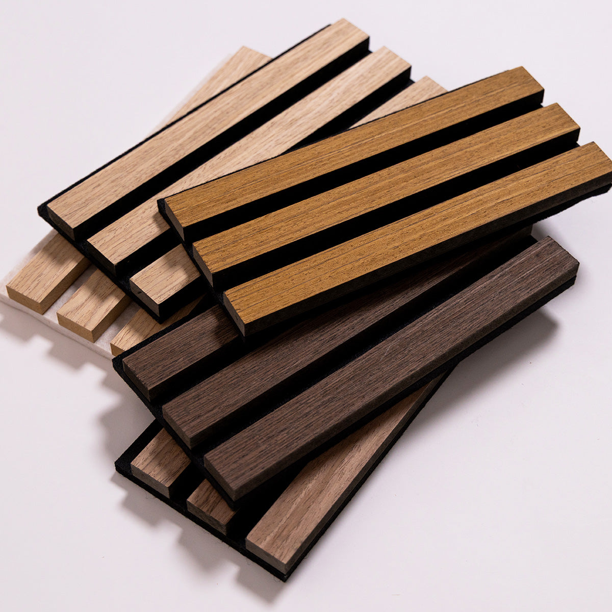 A stack of rectangular wood slats samples in multiple natural wood tones, including light tan, medium brown, and dark brown, arranged on a plain light background.
