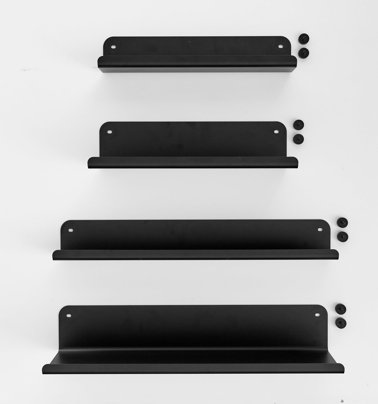 Four black metal floating shelves of varying heights, shown with their matching mounting screws on a clean white background.