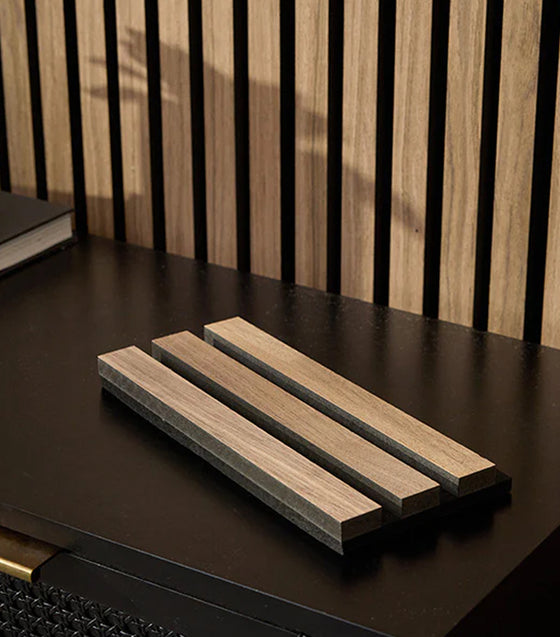 Wooden slats on a dark surface with a striped wall in the background