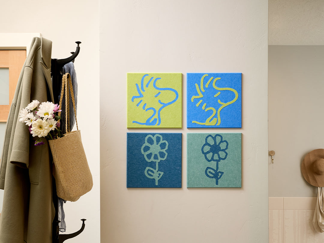 Decorative wall art with Woodstock Peanuts designs on a light-colored wall next to a coat and bag.