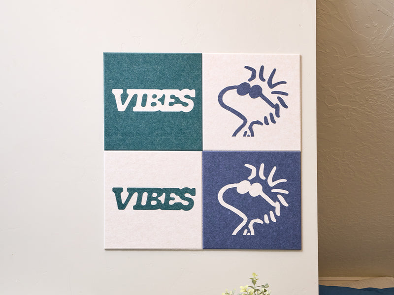 Decorative wall art with Peanuts Woodstock designs on a light-colored wall next to a coat and bag.