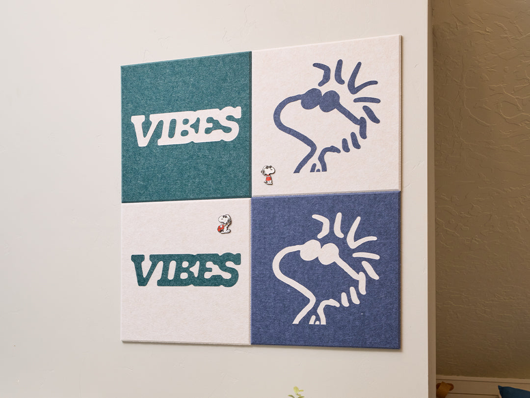 Decorative wall art with Peanuts Woodstock designs on a light-colored wall next to a coat and bag.