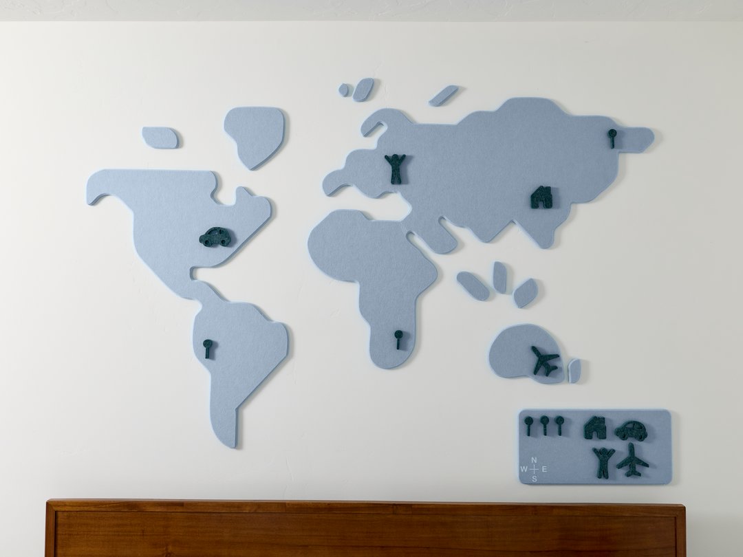 World map wall decoration on a white wall above head board of a bed.