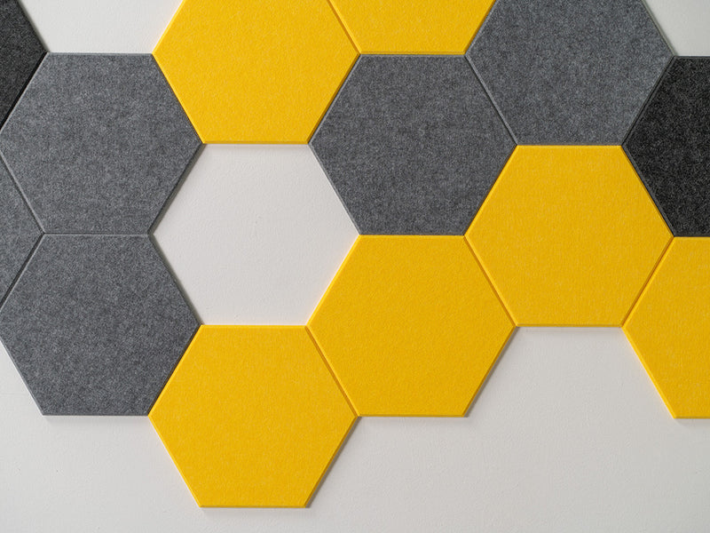 A Felt Right Wall Design wall-mounted art piece featuring a yellow and gray hexagonal pattern, with a beehive-inspired design, in a room with white walls