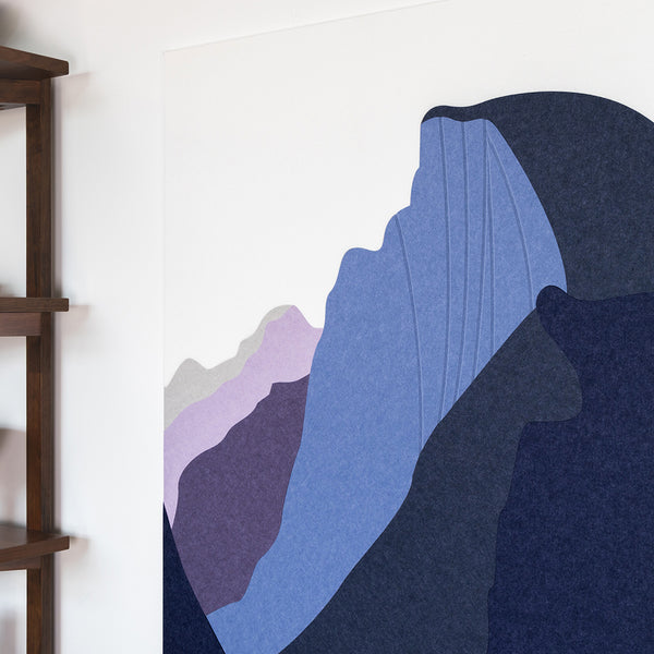 Abstract art piece with blue and purple shapes on a white wall next to a wooden shelf.