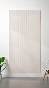Heathered off white Felt Right 4’ x 8’ PET felt panel with a linear and curvy pattern engraved into the material against a white wall. A plant and chair are in the foreground.
