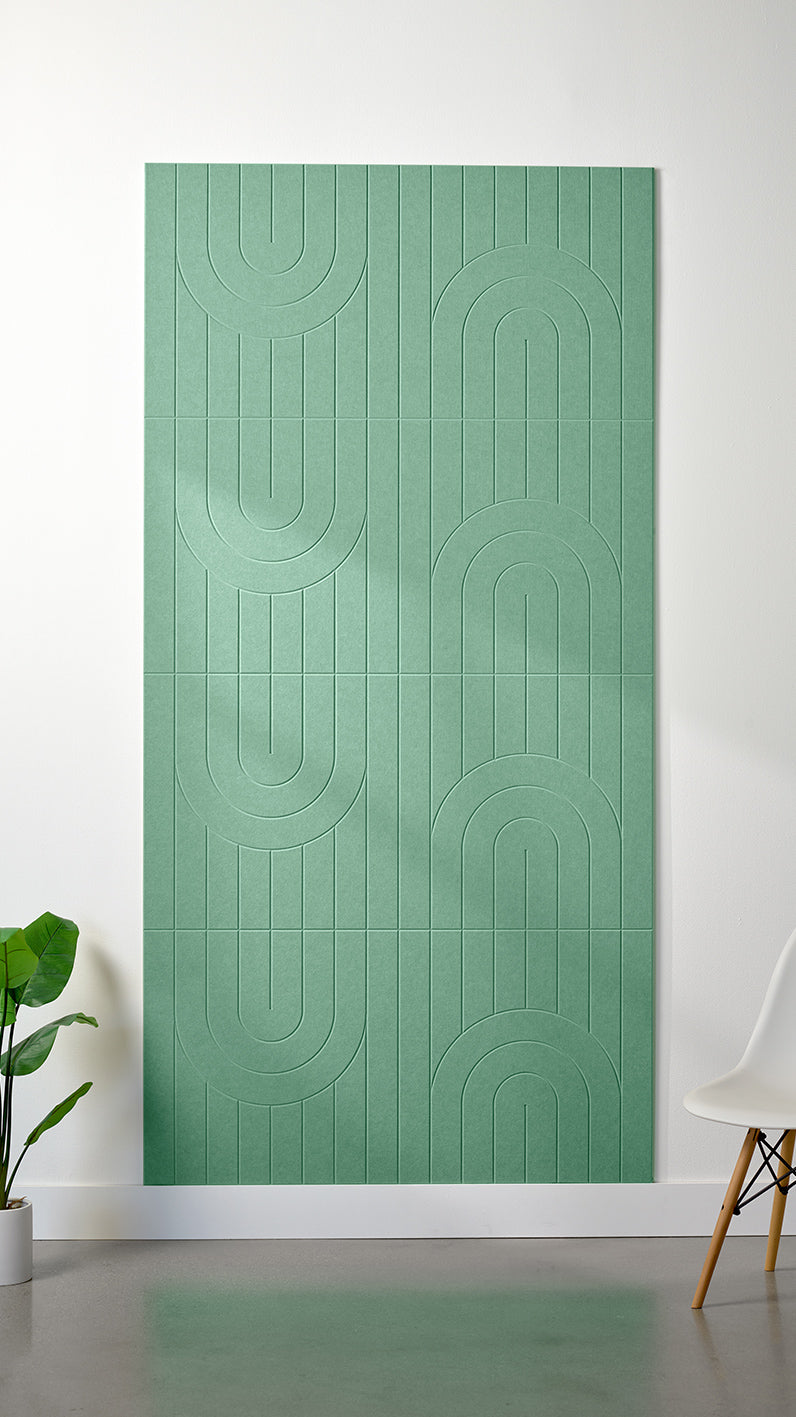 Mint green Felt Right 4’ x 8’ PET felt panel with a linear and curvy pattern engraved into the material against a white wall. A plant and chair are in the foreground.
