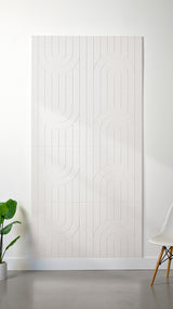 White Felt Right 4’ x 8’ PET felt panel with a linear and curvy pattern engraved into the material against a white wall. A plant and chair are in the foreground.
