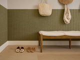 Square tile with engraved arch pattern in sage green, displayed on floor in entryway setting with wooden bench and accessorie