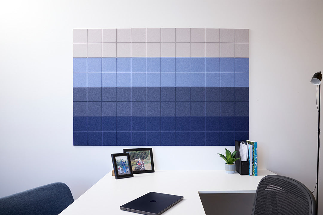 A Felt Right Wall Design that is wall-mounted blue ombre soundproofing panel installed above a desk in an office setting.
