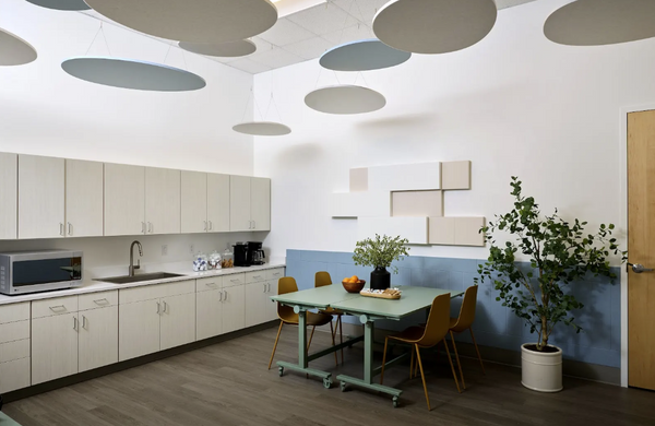 Modern kitchen with white cabinets, a dining table, and decorative ceiling lights.