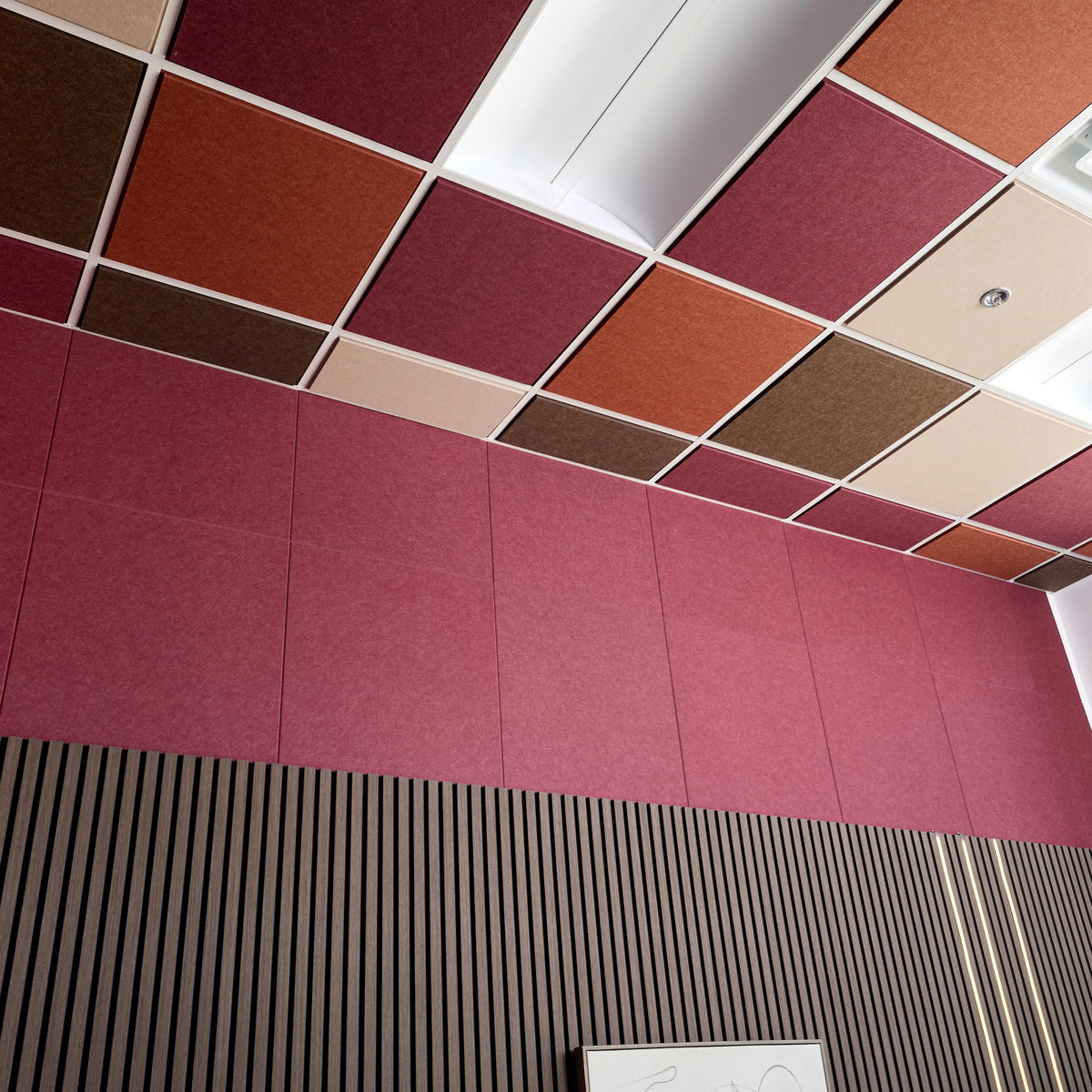 Colorblock felt drop ceiling tiles in burgundy, rust, cream and brown above a burgundy felt wall