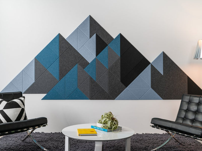 Geometric acoustic wall art with blue and black triangles in a modern living room setting.