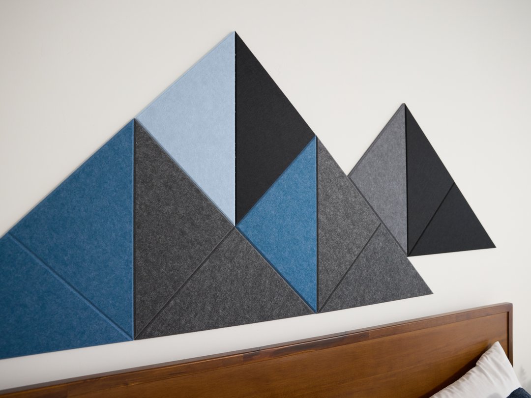 Geometric wall panels in blue and gray on a white wall above a wooden headboard.