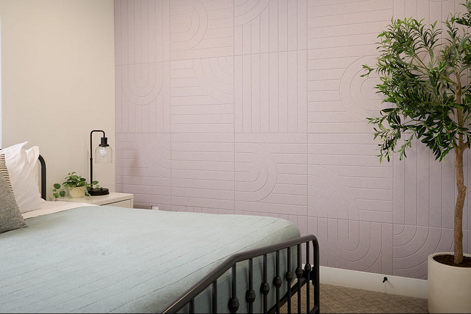 A Felt Right tile design in a grey zen garden look covering a wall in a bedroom next to a bed.