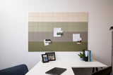 A Felt Right wall design that can work as a bulletin board with a green ombre design, mounted on a wall above a white desk. The board is decorated with notes, photos, and pins.