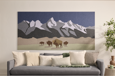 Framed wall art depicting snow-capped mountains with bison grazing in foreground against blue sky.