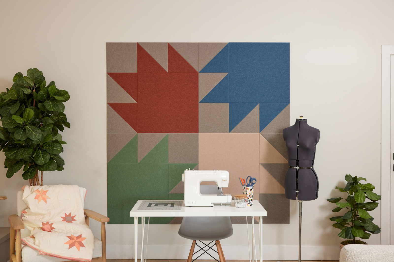 Sewing room with a sewing machine, mannequin, and colorful quilt design wall art.