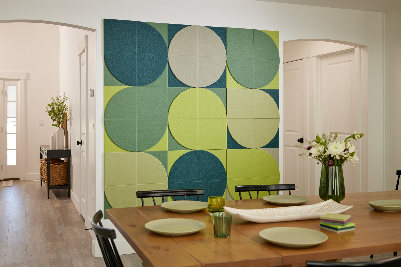 A Felt Right Wall art design using shades of green tiles creating a lily pad look on a wall in a dinning room by the table.