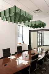 Green 3D cloud-shaped acoustic baffles suspended from ceiling above conference table in office space.