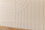 Ivory subway tiles with curved and linear relief patterns on wall above natural wood flooring.